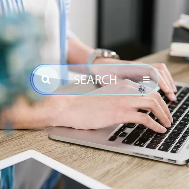 Hands typing on laptop with search bar overlay representing SEO optimization